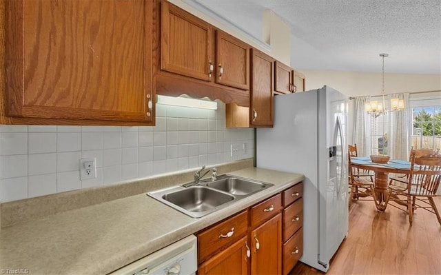 kitchen with vaulted ceiling, light wood-style floors, a sink, and brown cabinets