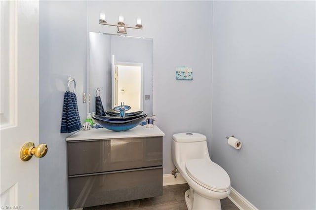 bathroom featuring baseboards, vanity, toilet, and wood finished floors