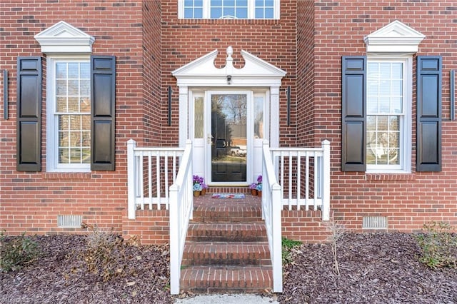 doorway to property featuring brick siding and crawl space