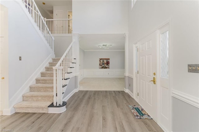 entrance foyer featuring stairs, a high ceiling, ornamental molding, and wood finished floors