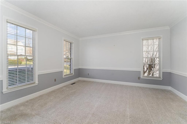 empty room with ornamental molding, a wealth of natural light, light carpet, and baseboards