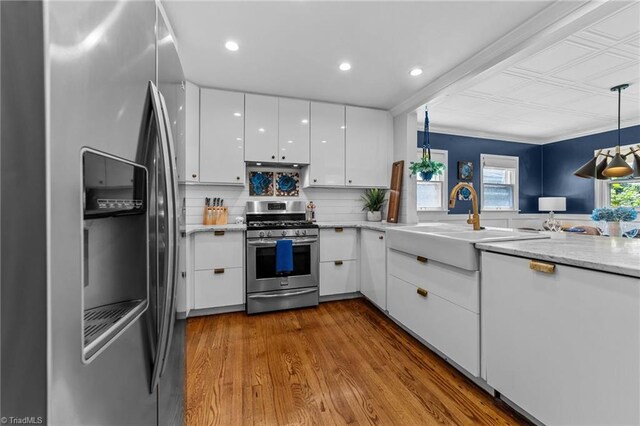 2607 Sherwood St, Greensboro, NC 27403 - kitchen with appliances with stainless steel finishes, white cabinets, wood finished floors, decorative light fixtures, and recessed lighting