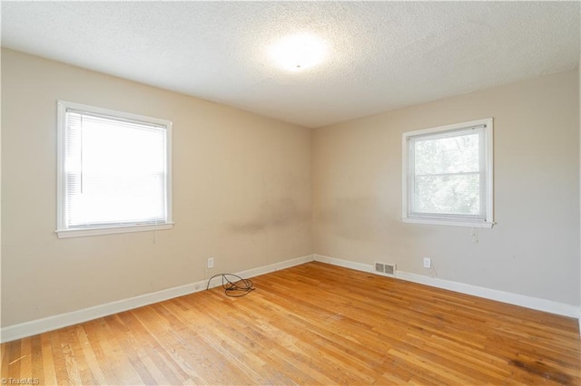 empty room featuring a textured ceiling and light wood-type flooring