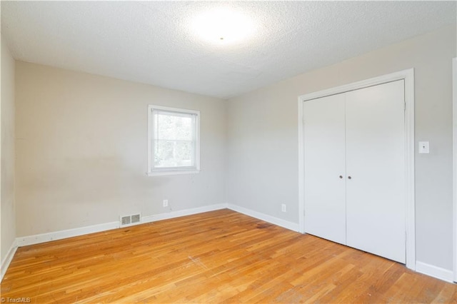 unfurnished bedroom with a closet, light hardwood / wood-style flooring, and a textured ceiling