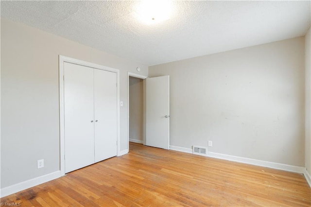 unfurnished bedroom featuring a closet, light hardwood / wood-style flooring, and a textured ceiling