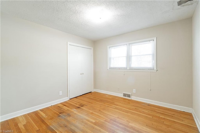 unfurnished room featuring light hardwood / wood-style floors and a textured ceiling