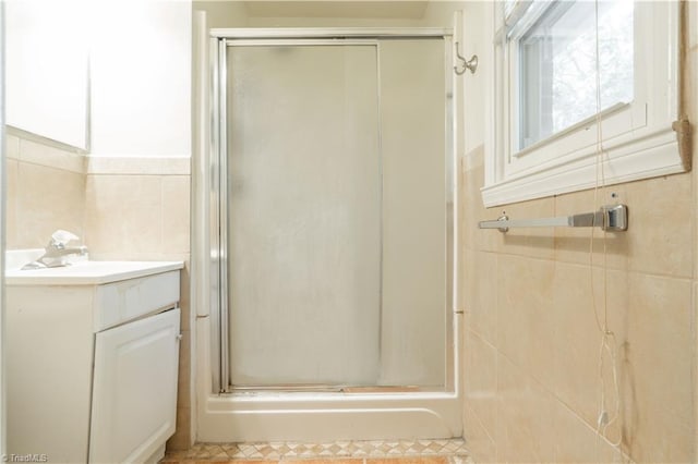 bathroom with tile flooring, tile walls, vanity, and a shower with door