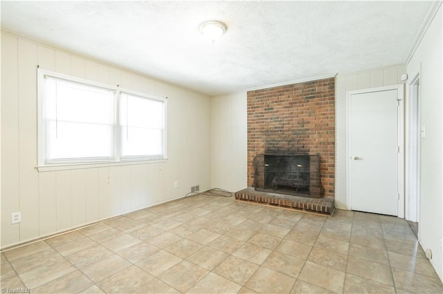 unfurnished living room with brick wall, crown molding, light tile floors, and a fireplace