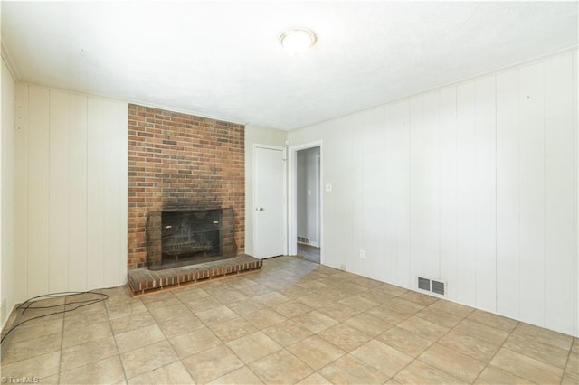 unfurnished living room featuring a fireplace, light tile flooring, and brick wall