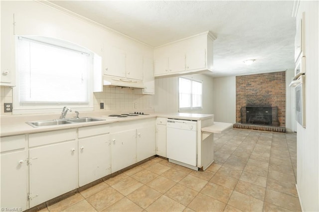 kitchen featuring white appliances, white cabinets, a fireplace, sink, and ornamental molding