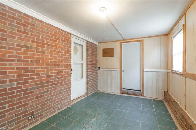 empty room with brick wall, dark tile flooring, and wood walls