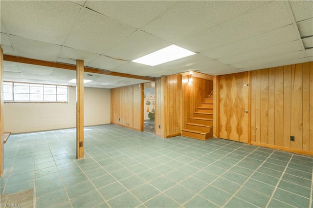 basement featuring wood walls, a paneled ceiling, and tile flooring