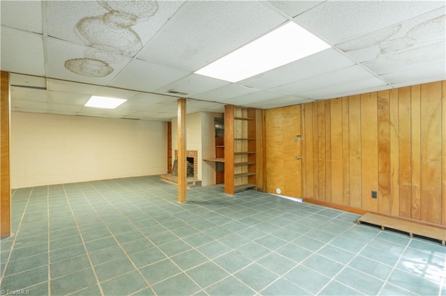 basement featuring wood walls, a paneled ceiling, and tile flooring