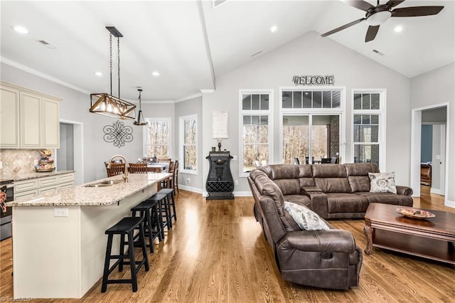 living room featuring lofted ceiling, sink, ceiling fan, ornamental molding, and light hardwood / wood-style floors