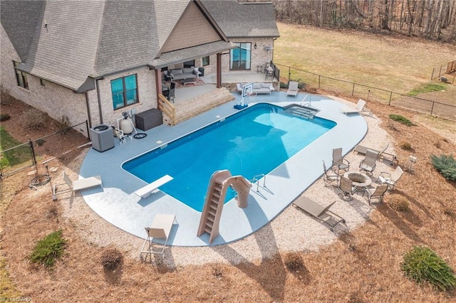 view of swimming pool with central air condition unit, a water slide, a diving board, an outdoor fire pit, and a patio