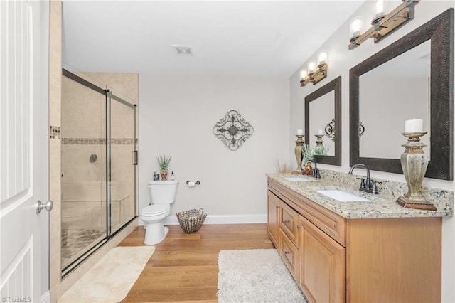 bathroom featuring wood-type flooring, toilet, an enclosed shower, and vanity