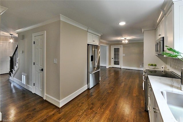 2700 Regency Dr, Winston-Salem, NC 27106 - kitchen featuring appliances with stainless steel finishes, dark wood-type flooring, baseboards, white cabinetry, and crown molding