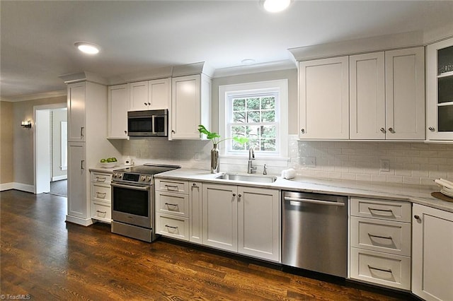 2700 Regency Dr, Winston-Salem, NC 27106 - kitchen with appliances with stainless steel finishes, a sink, crown molding, backsplash, and dark wood-style flooring