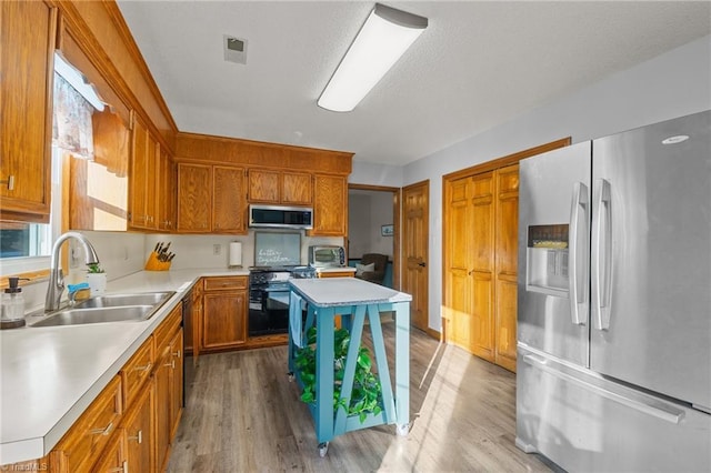 kitchen with sink, stainless steel appliances, and light wood-type flooring