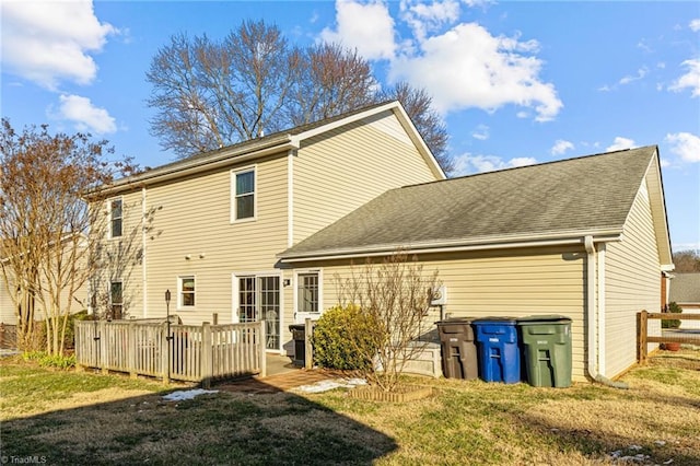 rear view of property featuring a deck and a lawn