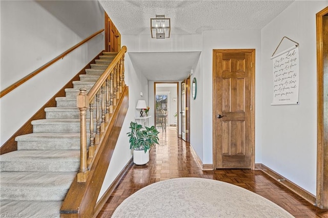 foyer with a textured ceiling and dark parquet floors