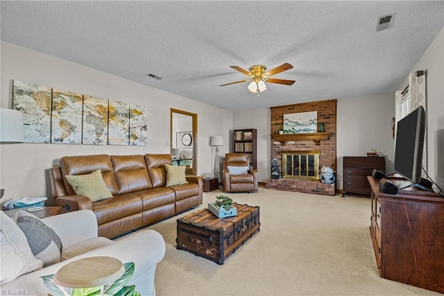 living room featuring a brick fireplace, a textured ceiling, light colored carpet, and ceiling fan