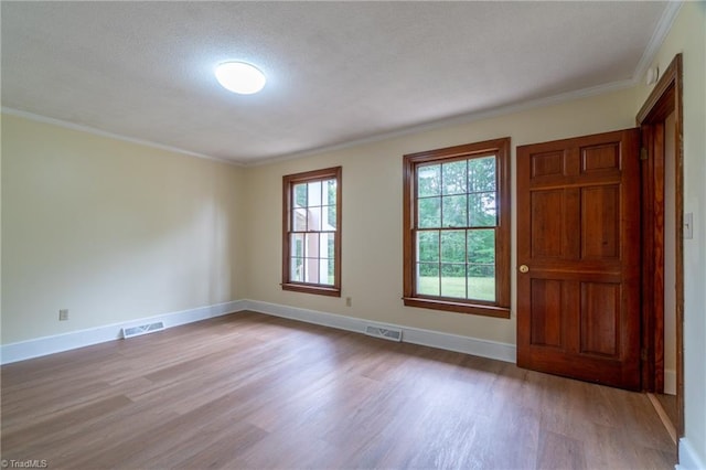 unfurnished room featuring ornamental molding, light hardwood / wood-style flooring, and a textured ceiling