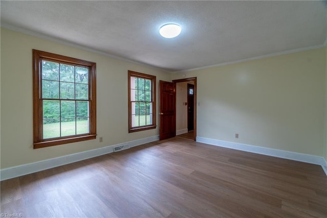 spare room with hardwood / wood-style flooring, ornamental molding, and a textured ceiling