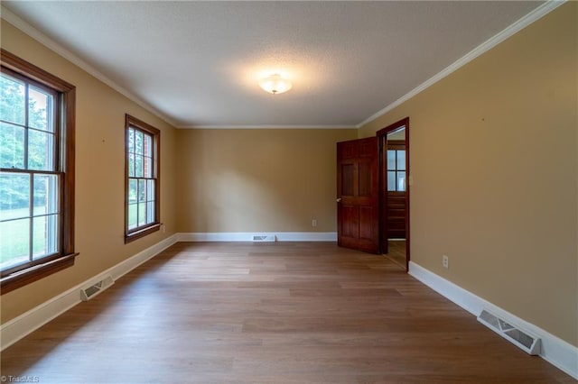 unfurnished room with a textured ceiling, crown molding, and light hardwood / wood-style floors