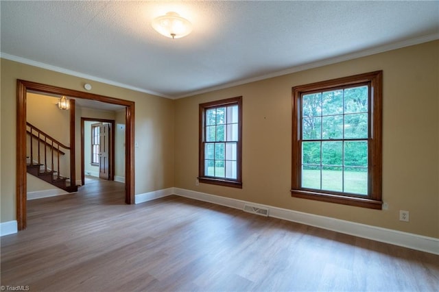 empty room featuring hardwood / wood-style flooring, a textured ceiling, and a healthy amount of sunlight