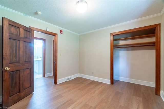 unfurnished bedroom with a closet, ornamental molding, light wood-type flooring, and a textured ceiling