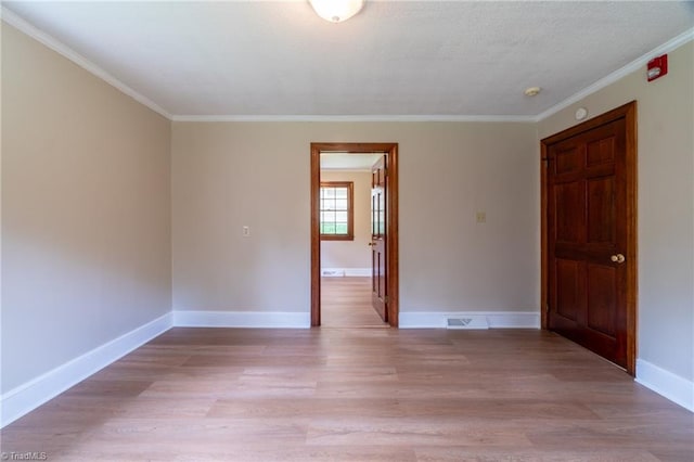 spare room featuring ornamental molding and light wood-type flooring