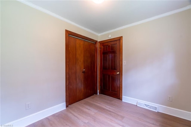 spare room featuring crown molding and light hardwood / wood-style floors