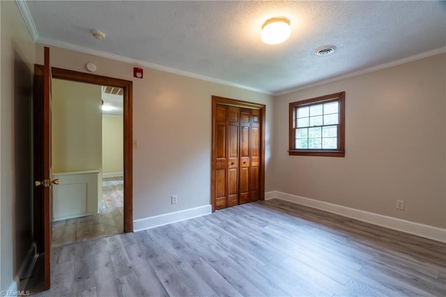 unfurnished bedroom featuring a closet, crown molding, hardwood / wood-style flooring, and a textured ceiling