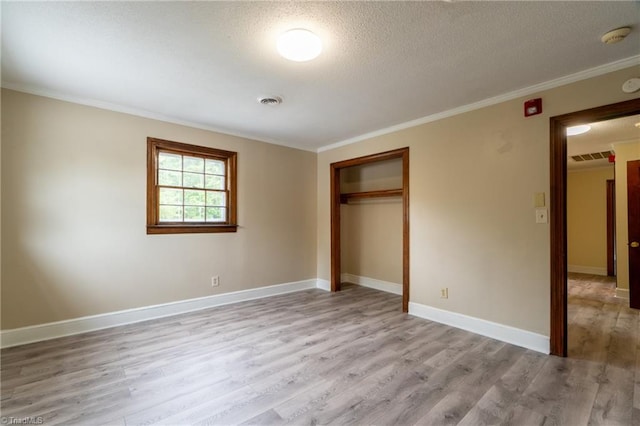 unfurnished bedroom featuring a closet, ornamental molding, light wood-type flooring, and a textured ceiling