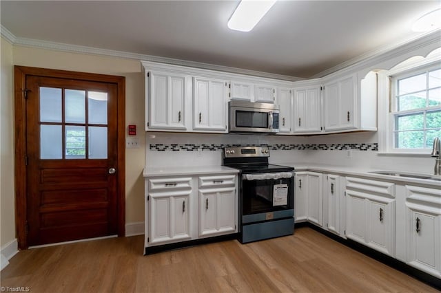 kitchen with light wood-type flooring, sink, stainless steel appliances, and white cabinets