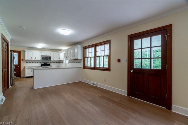 kitchen with white cabinets, stainless steel appliances, plenty of natural light, and light hardwood / wood-style floors