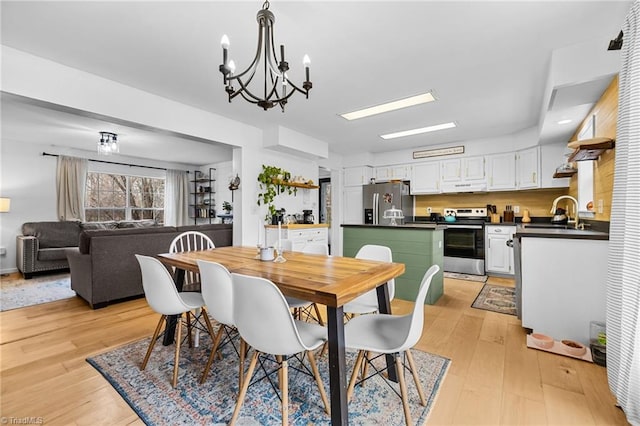 dining area featuring an inviting chandelier, light hardwood / wood-style floors, and sink