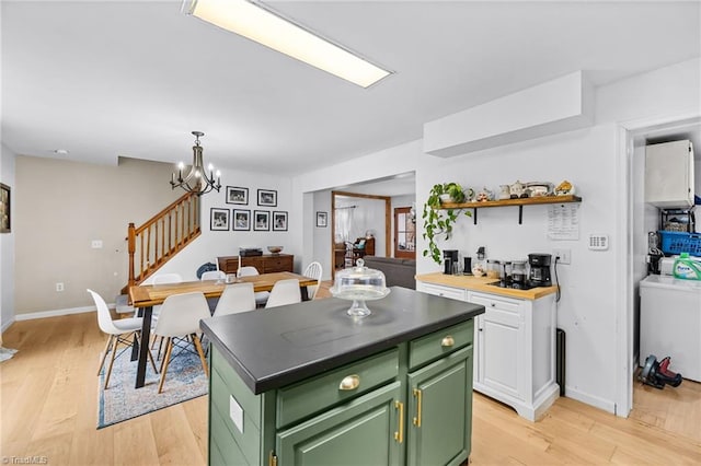 kitchen featuring white cabinets, a center island, washer / clothes dryer, a chandelier, and green cabinetry