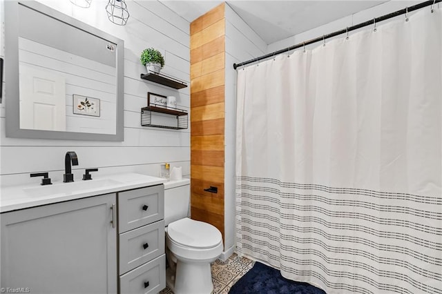 bathroom with toilet, vanity, tile patterned flooring, and wooden walls