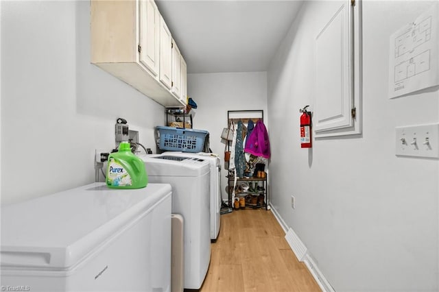 laundry area featuring cabinets, light hardwood / wood-style floors, and washer and clothes dryer