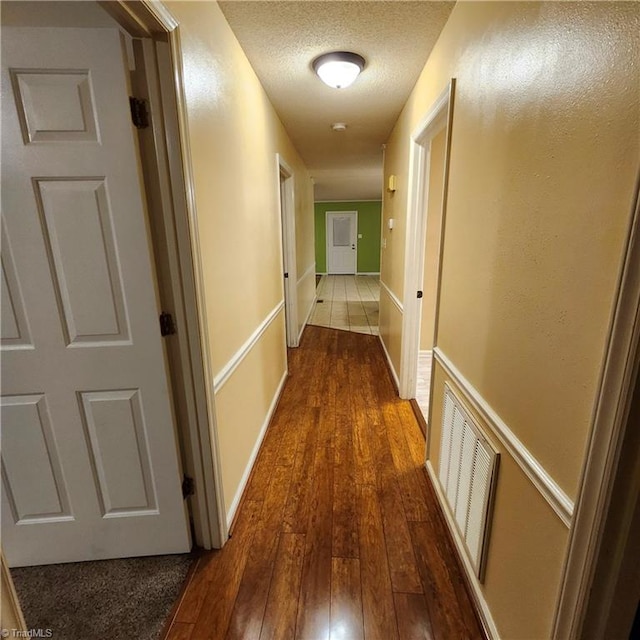 corridor featuring a textured ceiling and dark hardwood / wood-style flooring