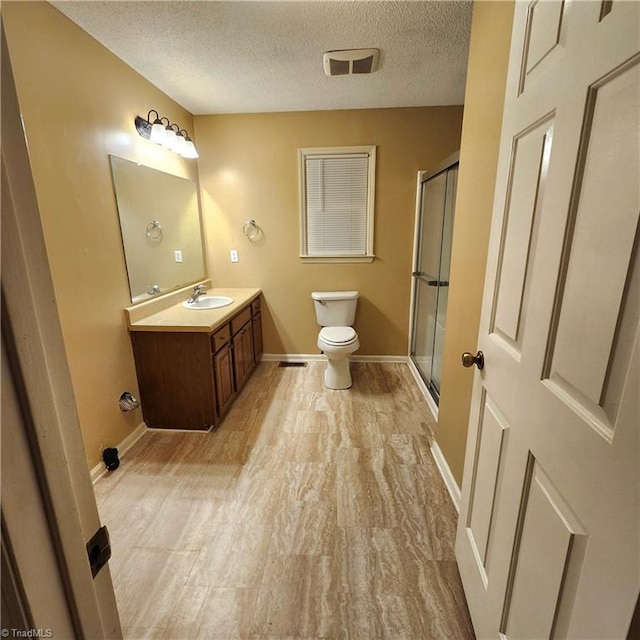 bathroom with toilet, a shower with door, hardwood / wood-style flooring, a textured ceiling, and vanity