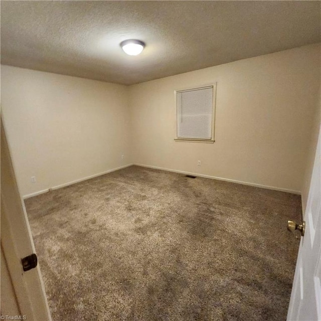 carpeted empty room featuring a textured ceiling