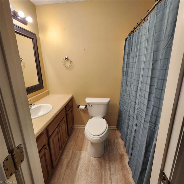 bathroom with a shower with shower curtain, hardwood / wood-style flooring, vanity, and toilet