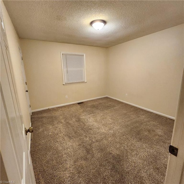 carpeted empty room featuring a textured ceiling