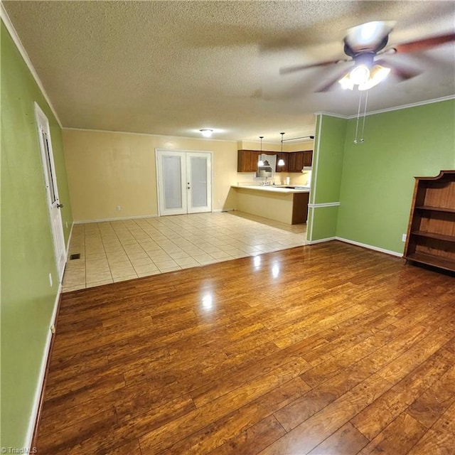 unfurnished living room featuring light wood-type flooring, a textured ceiling, ceiling fan, and crown molding