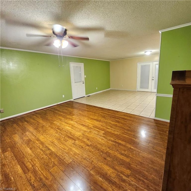 empty room with ceiling fan, a textured ceiling, light wood-type flooring, and ornamental molding