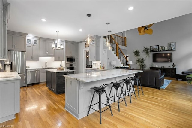 kitchen with appliances with stainless steel finishes, hanging light fixtures, and light hardwood / wood-style flooring