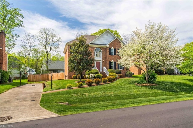 traditional home with fence, a front lawn, driveway, and brick siding